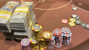 Ein Mann sitzt an einem Pokertisch und betrachtet nachdenklich eine leere Puppe, die wie ein Geldbündel aussieht.