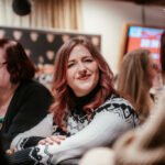 Ein stimmungsvolles Bild eines Pokertischs mit grüner Filzoberfläche, umgeben von Spielern, die Karten halten und Chips stapeln. Die Spieler sind konzentriert und vertieft in