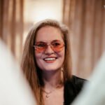 Ein Mann sitzt an einem Pokertisch, umringt von anderen Spielern. Er hält Karten in der Hand und schaut konzentriert auf den Tisch. In der Mitte des Tisches liegen Pokerchips