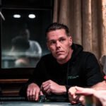 Ein professioneller Pokertisch mit grünem Filz, umgeben von Spielern mit Karten und Chips.