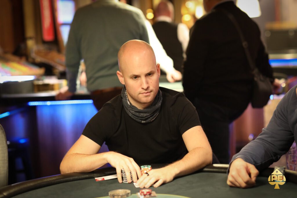 Ein Mann und eine Frau spielen eine Partie Poker in einem eleganten Casino. Der Mann hat Karten in der Hand, während die Frau konzentriert auf ihre Karten schaut. Die Szene ist durch die luxuriöse Ein