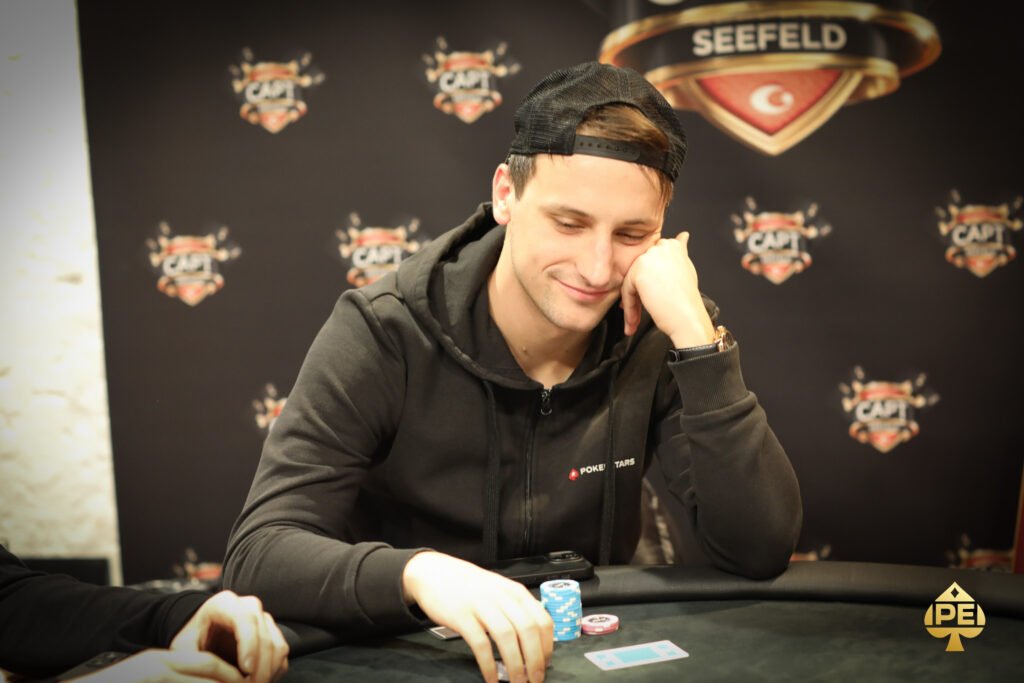 Ein eleganter Pokertisch mit grüner Filzdecke, umgeben von Stühlen und beleuchtet von einer eleganten Deckenleuchte. Auf dem Tisch liegen Spielkarten, Pokerchips und Get