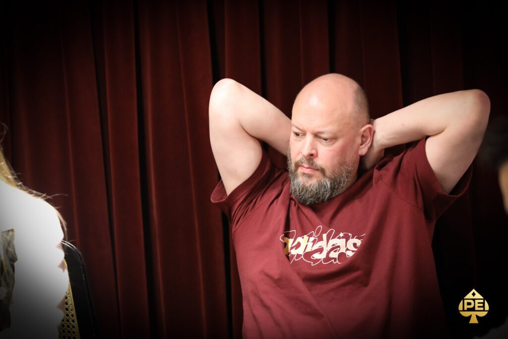 Ein professioneller Pokerspieler, der konzentriert an einem Pokertisch sitzt und seine Karten betrachtet, während er an einem Turnier teilnimmt.