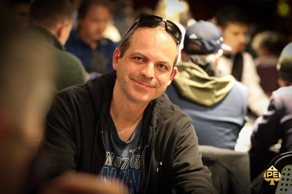 Ein professioneller Pokerspieler konzentriert sich am Pokertisch, umgeben von Karten und Chips, während er seine Strategie überdenkt.