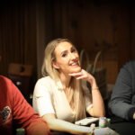 Ein Mann und eine Frau sitzen an einem Pokertisch und betrachten konzentriert ihre Karten. Die Szene ist in einem eleganten Pokerraum mit grünen Filzdecken und Pokerchips im Vordergrund