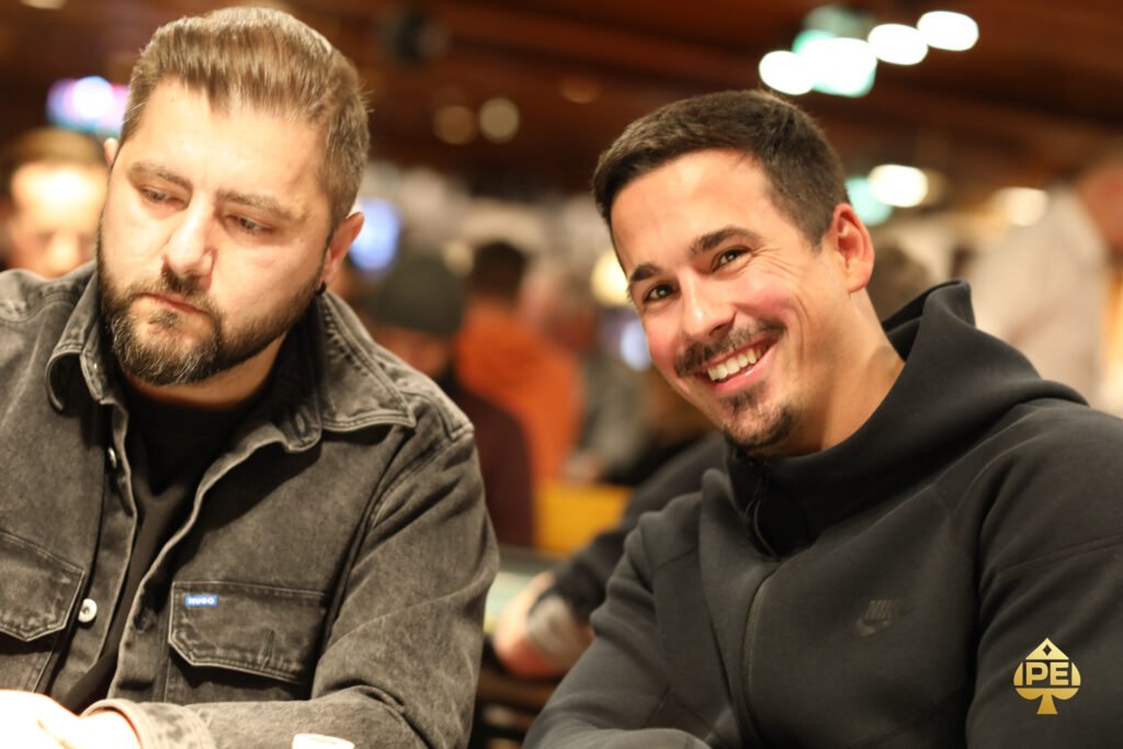 Ein Mann sitzt an einem Pokertisch, umgeben von Spielkarten und Jetons. Er hat eine ernste Miene und studiert konzentriert seine Karten.
