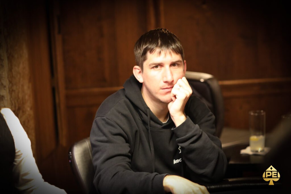Ein Mann und eine Frau spielen Poker an einem eleganten Tisch in einem luxuriösen Casino. Der Mann hat eine ernste Miene und hält Karten in der Hand, während die Frau konzentriert auf ihre eigenen Karten
