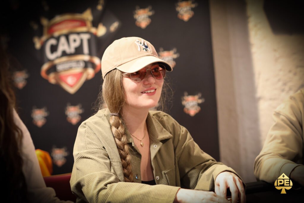 Ein professioneller Pokertisch während eines Turniers mit Spielkarten, Pokerchips und Getränken, umgeben von konzentrierten Spielern in einem eleganten Raum mit gedämpftem Licht.