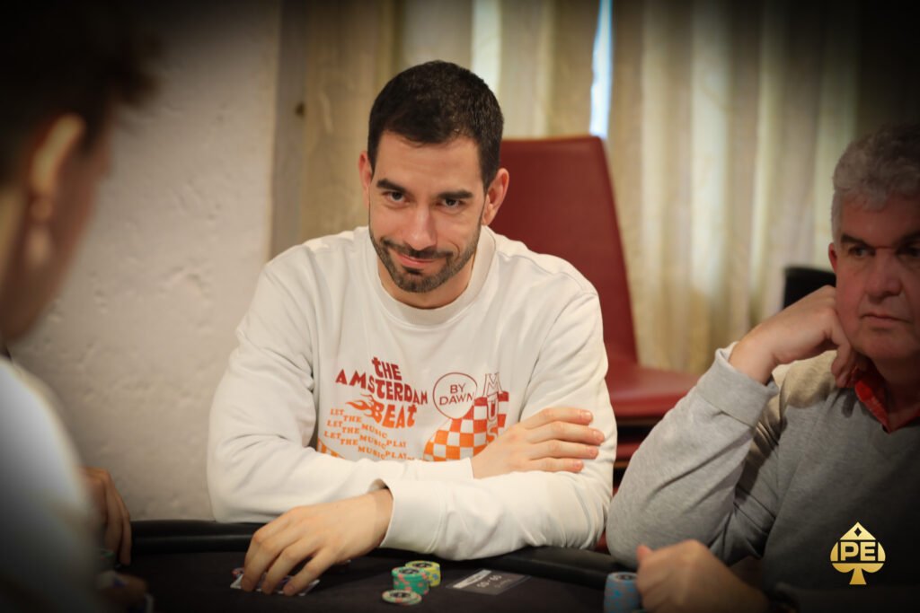 Ein professioneller Pokertisch mit grünem Filz, umgeben von Spielern, die Konzentration und Spannung ausstrahlen. Karten und Chips liegen auf dem Tisch, während im Hintergrund eine stilvolle