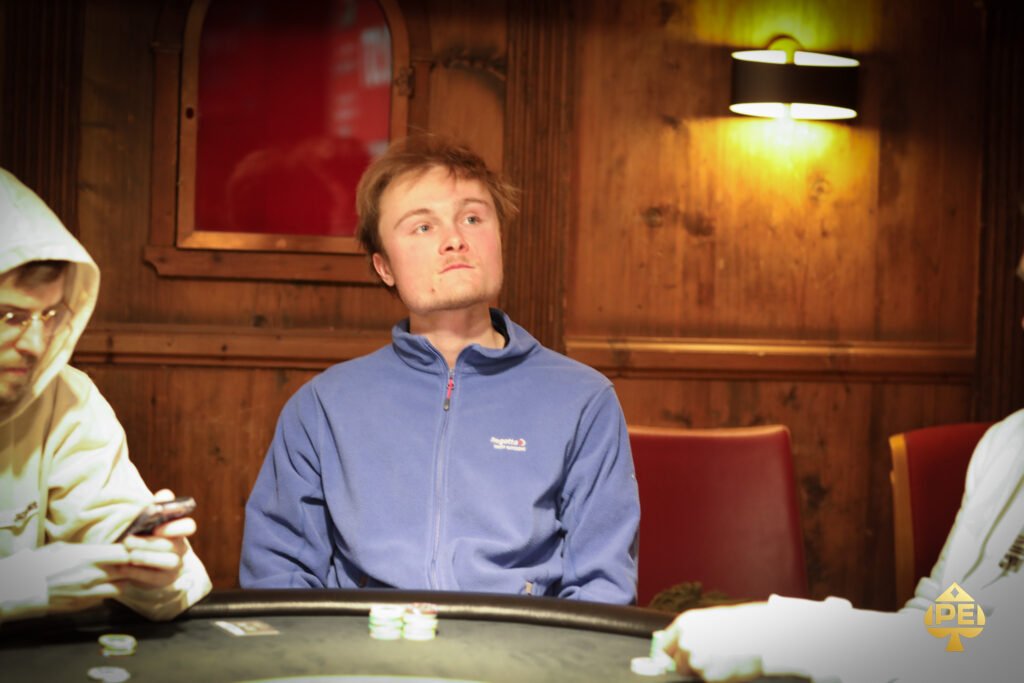 Ein eleganter Pokertisch mit grünem Filz, umgeben von luxuriösen Ledersesseln, Gläsern mit Getränken und einer glänzenden Decke. In der Mitte des Tisches