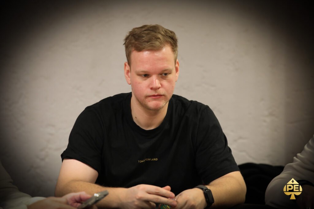 Ein buntes Pokertisch-Layout mit Spielkarten, Pokerchips, Getränken und anderen Spielutensilien, die auf einem grünen Filz verteilt sind. In der Mitte des Tisches befindet