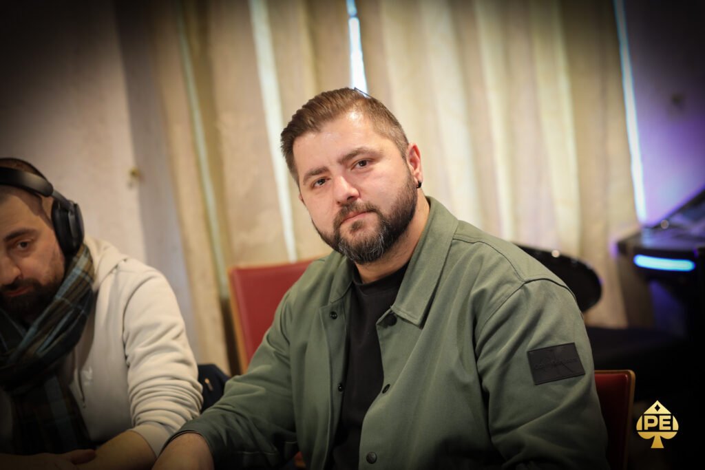 Ein Mann und eine Frau sitzen an einem Pokertisch in einem eleganten Casino. Der Mann hat gerade seine Karten aufgedeckt und die Frau schaut gespannt auf ihre eigenen Karten. Die Atmosphäre ist konzent