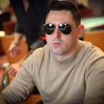 Ein Mann und eine Frau sitzen an einem Pokertisch und betrachten konzentriert ihre Karten. Der Mann hat einen Stapel Chips vor sich liegen, während die Frau mit einem ernsten Gesichtsausdruck ihre Hand