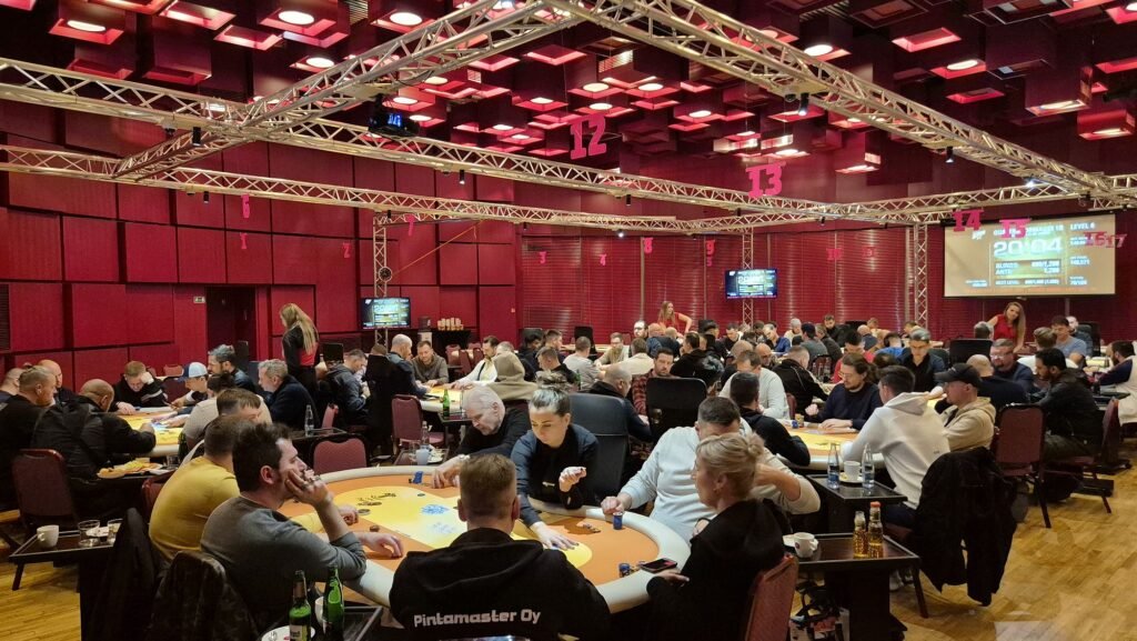 Ein professioneller Pokerspieler mit einer Kappe und Sonnenbrille, der konzentriert an einem Pokertisch sitzt und Karten hält, während er sein nächstes Spiel plant.
