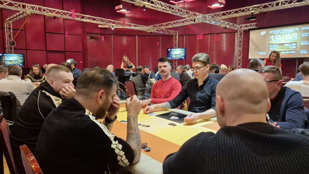 Ein Mann und eine Frau sitzen an einem Pokertisch und spielen Poker. Der Mann hält Karten in der Hand, während die Frau konzentriert auf ihre Karten schaut. Im Hintergrund sind Pokerchips und Get