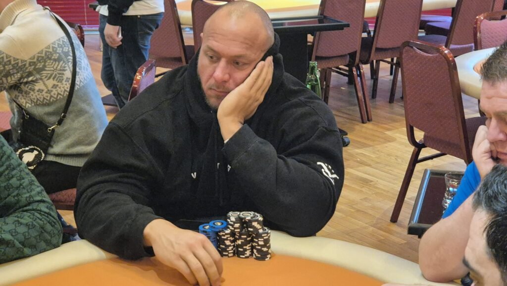 Ein Mann und eine Frau sitzen an einem Pokertisch und spielen eine Partie Poker. Der Mann hat gerade seine Karten angeschaut und scheint nachzudenken, während die Frau mit einem selbstbewussten Blick auf ihre K