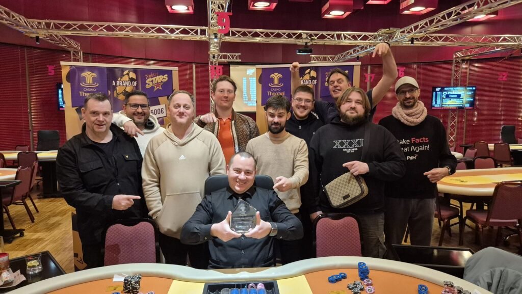 Ein Mann und eine Frau sitzen an einem Pokertisch und spielen eine Partie Poker. Der Mann hat gerade eine Hand gespielt und schaut gespannt auf die Karten in der Mitte des Tisches, während die Frau nach