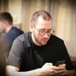 Ein Mann und eine Frau sitzen an einem Pokertisch und spielen Karten. Der Mann hat einen Anzug an, die Frau trägt ein elegantes Abendkleid. Die Atmosphäre ist konzentriert und spannend