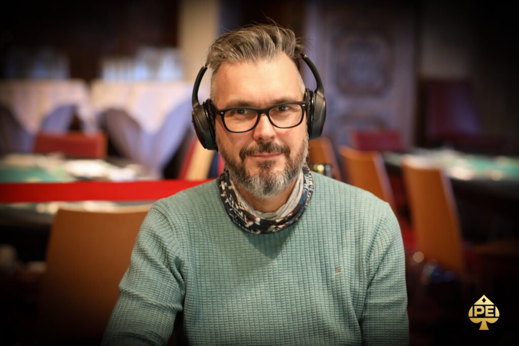 Ein Mann in einem schwarzen Anzug und einer schwarzen Sonnenbrille spielt Poker an einem eleganten Tisch in einem luxuriösen Casino.