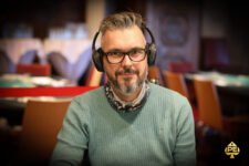 Ein Mann in einem schwarzen Anzug und einer schwarzen Sonnenbrille spielt Poker an einem eleganten Tisch in einem luxuriösen Casino.